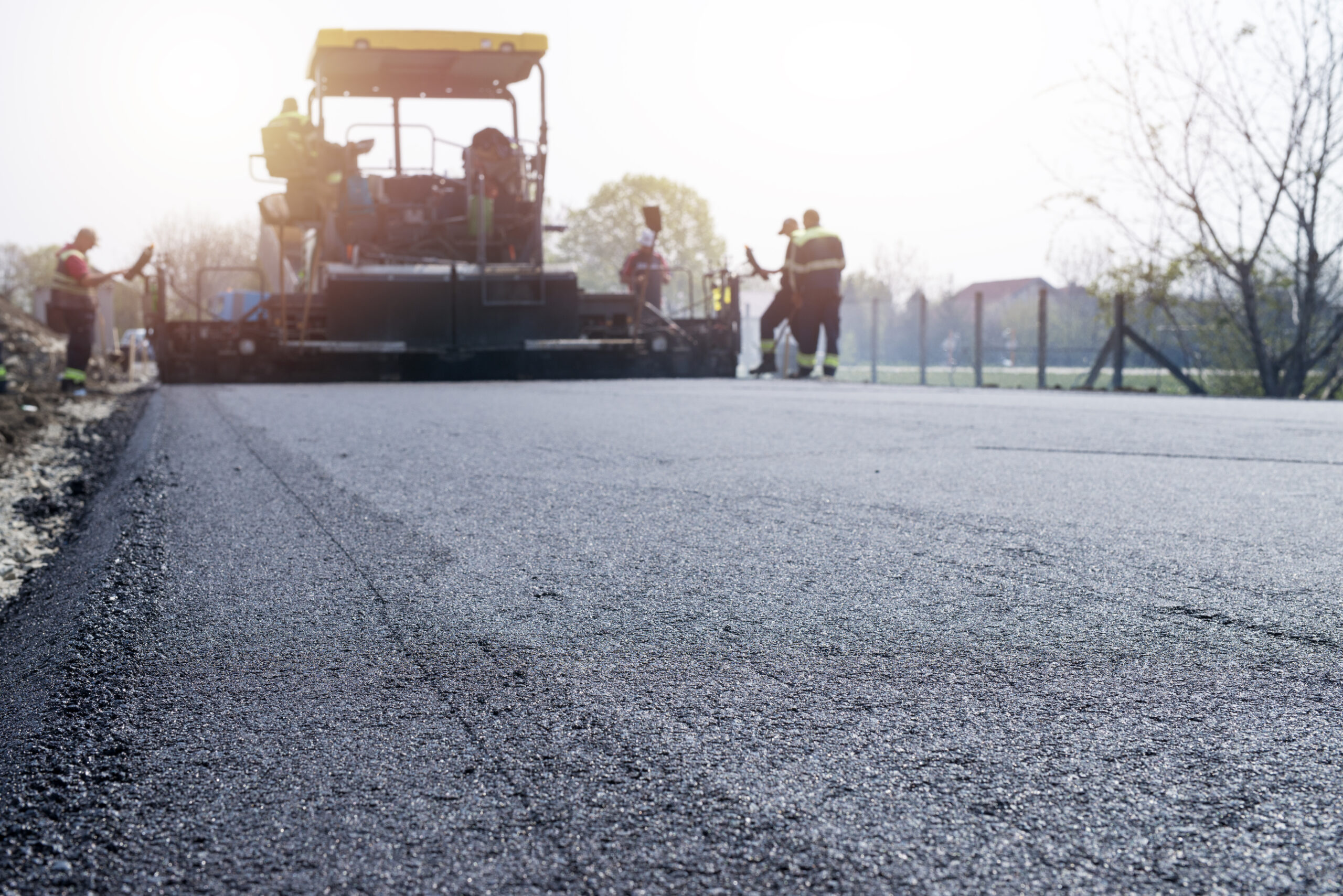 workers placing new coating of asphalt on the road.